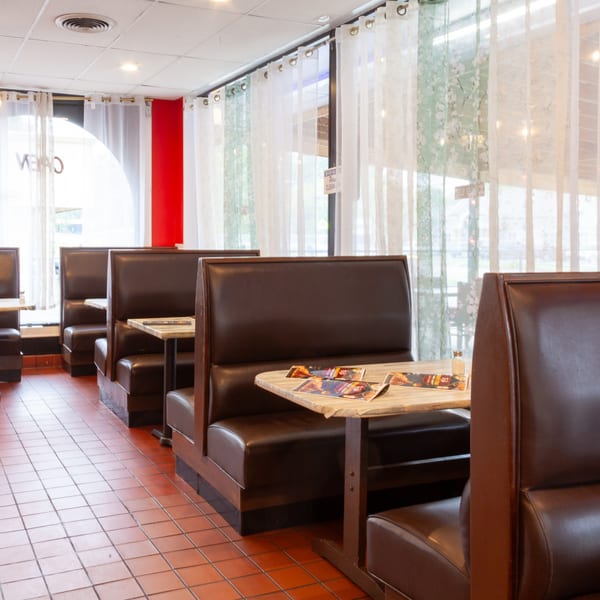 Empty Indian 5 Stars Restaurant dining area with brown booths, wooden tables, and tiled floor.