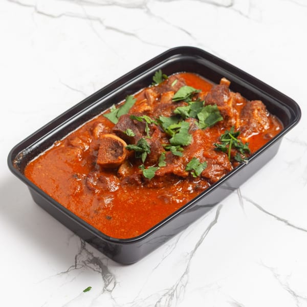 Indian 5 Stars Restaurant's lamb curry with rich red sauce and fresh cilantro in a black container.
