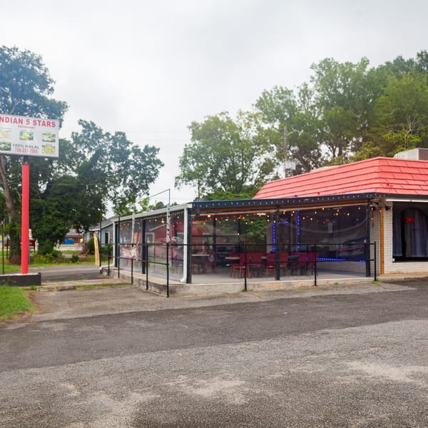 Exterior of Indian 5 Stars Restaurant with a red roof, outdoor seating, and a sign.