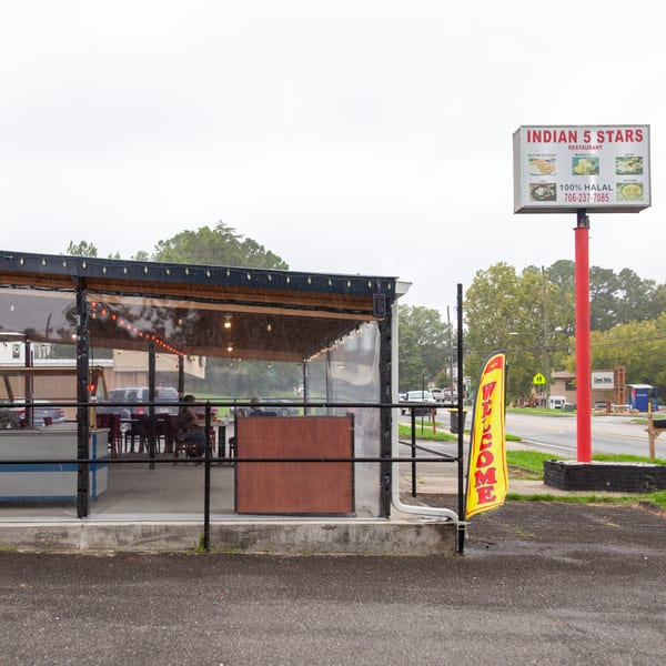 Exterior of Indian 5 Stars Restaurant with a large sign and covered outdoor seating area.