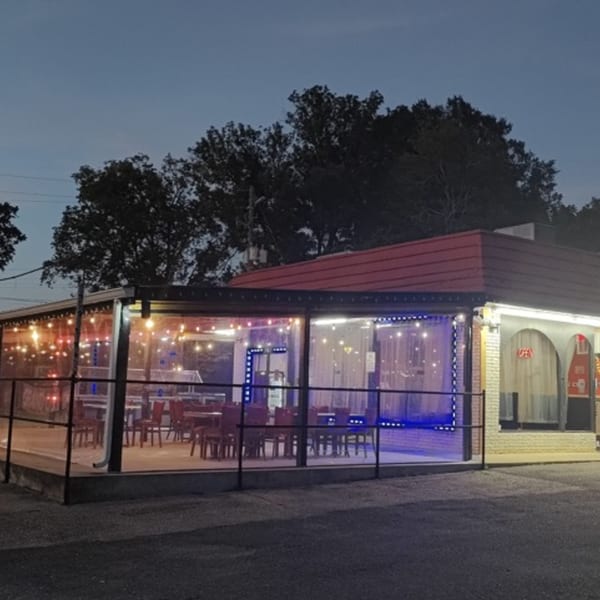 Exterior of Indian 5 Stars Restaurant at dusk, with an illuminated outdoor patio and red roof.