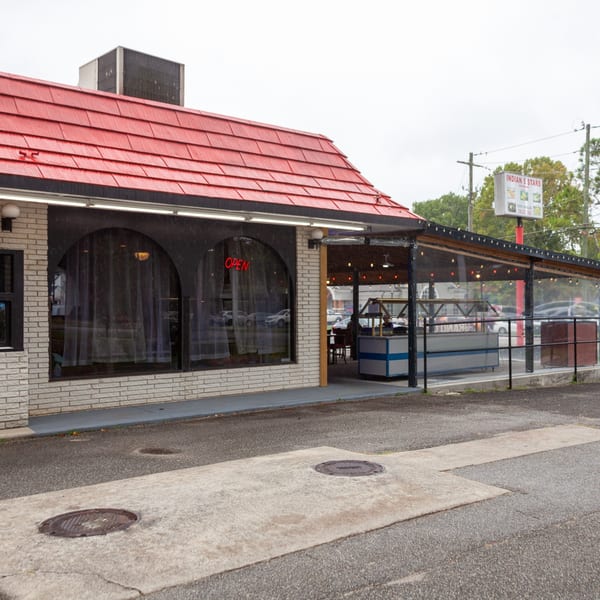 Exterior of Indian 5 Stars Restaurant with a red roof, white brick, and an outdoor patio.