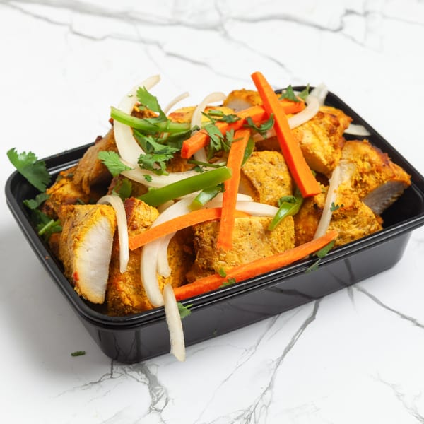 Indian 5 Stars Restaurant's chicken tikka, garnished with fresh cilantro, onions, and carrots.
